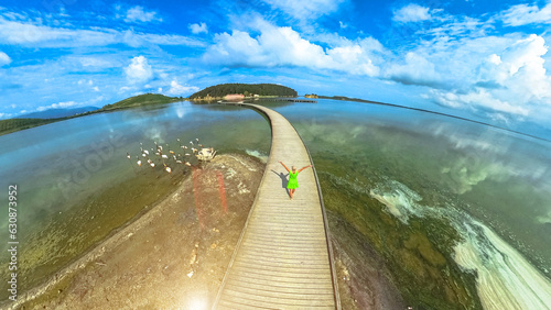 drone view of woman tourist walking on pedestrian bridge to site on Zvernec Island in Narta Lagoon. Location of the Zvernec St. Mary Monastery near Vlora city on southwestern Albania. photo