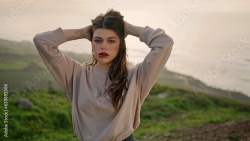 Beautiful girl posing hill seashore with ocean backdrop close up. Stylish model.