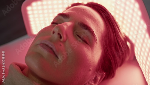 Woman relaxing led light on photodynamic procedure close up. Client phototherapy photo