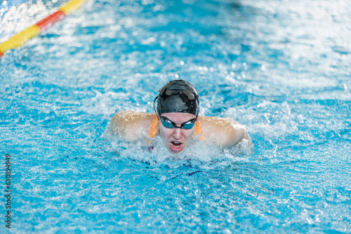 Female competitive swimmer moving through the water performing the butterfly stroke during swimming training  front view.