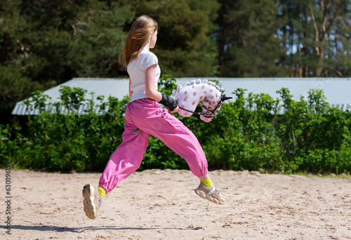 Girl jumping on hobby horse. Champion. Horse sport. Summer light. Green outdoor trees background. The Cavaletti route. Child sport. Banner photo