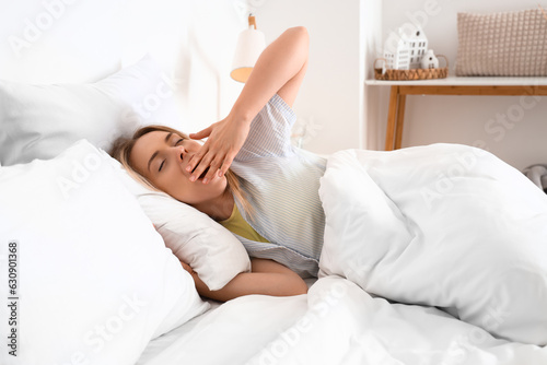 Young woman waking up in bed