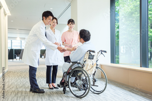 車椅子に乗った患者と握手をする医師
