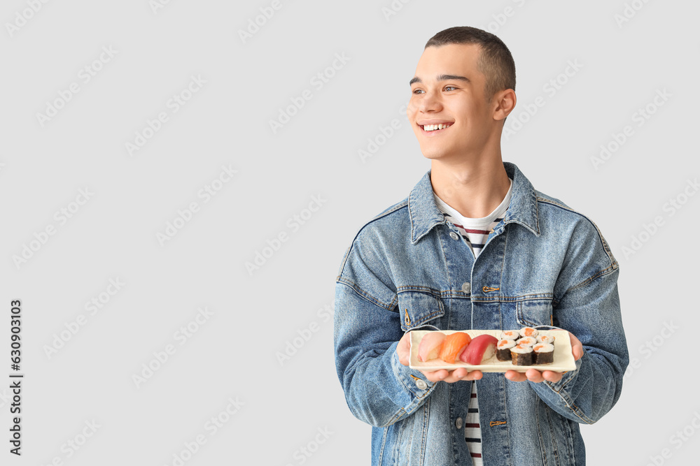 Young man with tasty sushi on light background Young man with tasty sushi on light background