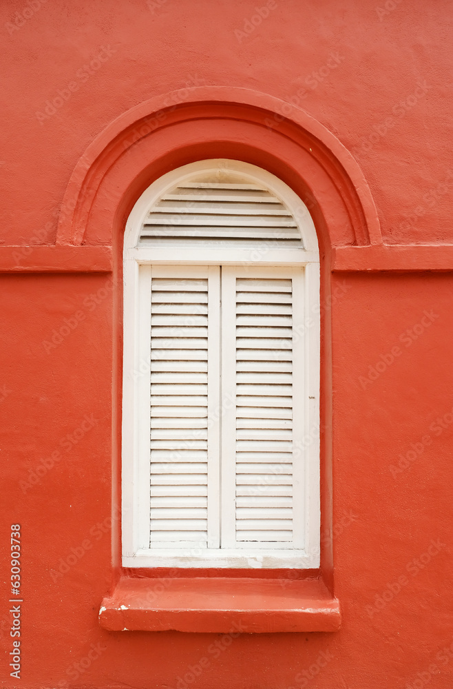 A picture of white classic window on classic red building