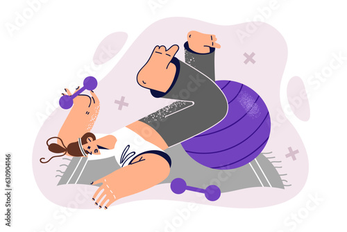 Athletic woman lies on fitness mat with dumbbells and pilates ball and suffers from injury in gym