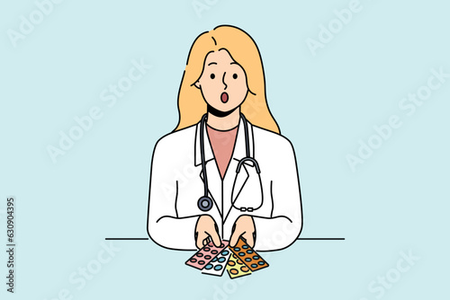 Surprised woman doctor with pills in blisters feels distrustful of drugs that can harm patient. Skeptical girl doctor with stethoscope around neck does not want to recommend untested medicines