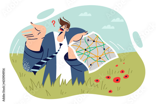 Confused business man stands on field with map of area and spreads arms, not knowing where to go