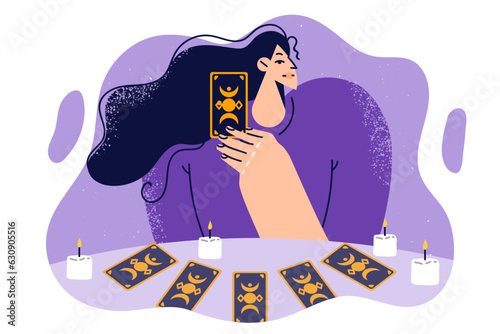 Woman predictor or fortune teller with tarot cards laid out on table with candles predicts future.