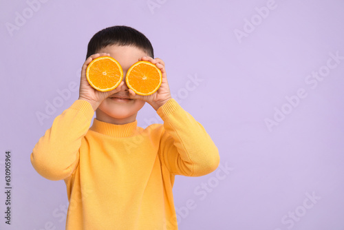 Cute little boy with oranges on lilac background © Pixel-Shot