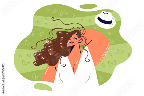 Woman lies on lawn with green grass and enjoys warm sunshine and presence of free time