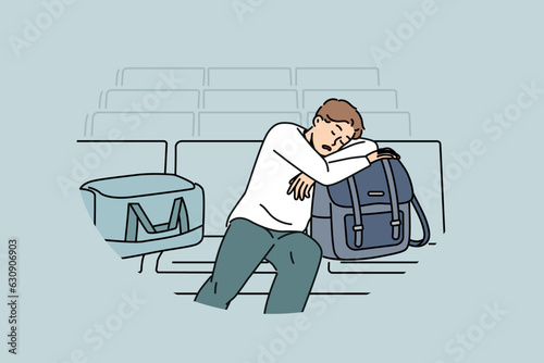 Sleeping man sits in lounge area at airport and waits for arrival of plane delayed due to bad weather. Tired guy airport passenger with bags and luggage waiting for flight and travel