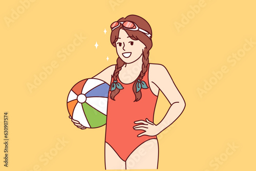Little girl with water volleyball ball is dressed in bathing suit for visiting pool or beach. Happy child rejoices at opportunity to visit aqua park and leave ball in children pool