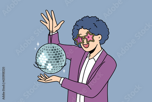 Funny man with disco ball with curly wig on head came to nightclub or dance floor to have fun and relax. Young guy enjoys atmosphere of music festival or disco party for party people