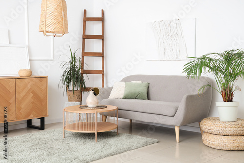 Interior of light living room with sofa, table and houseplants