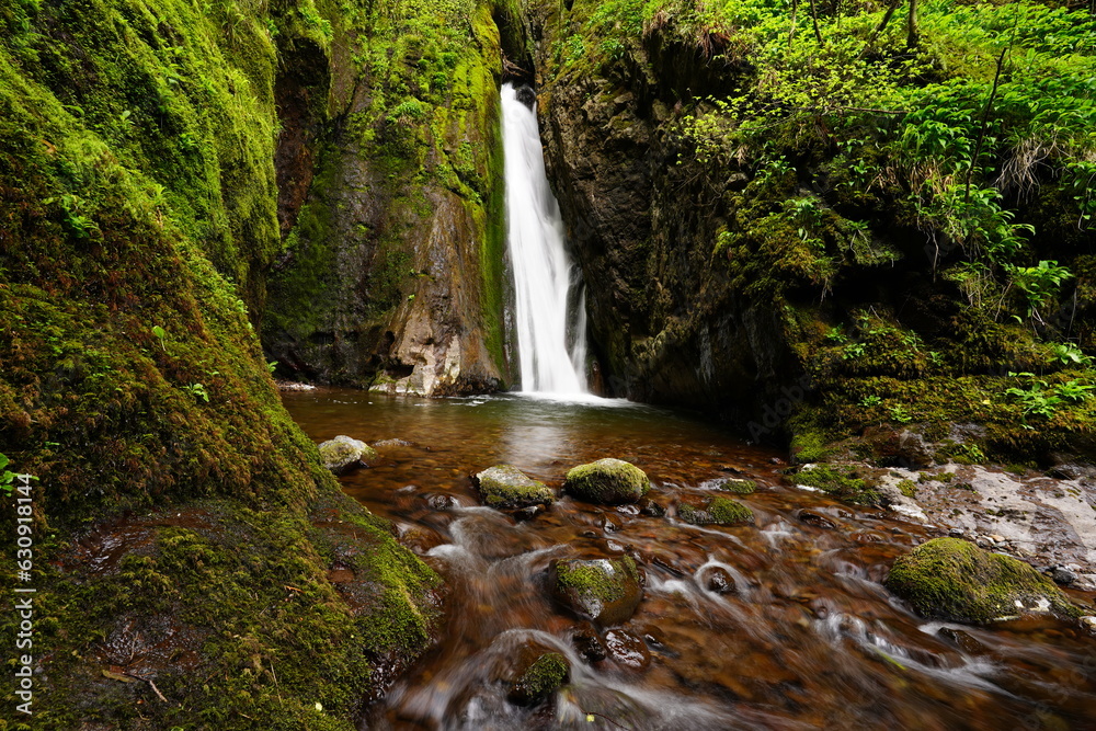 waterfall between mossy rocks