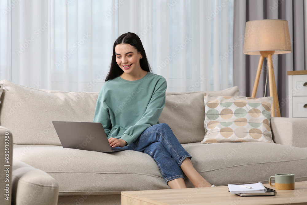 Happy woman working with laptop on sofa at home Happy woman working with laptop on sofa at home