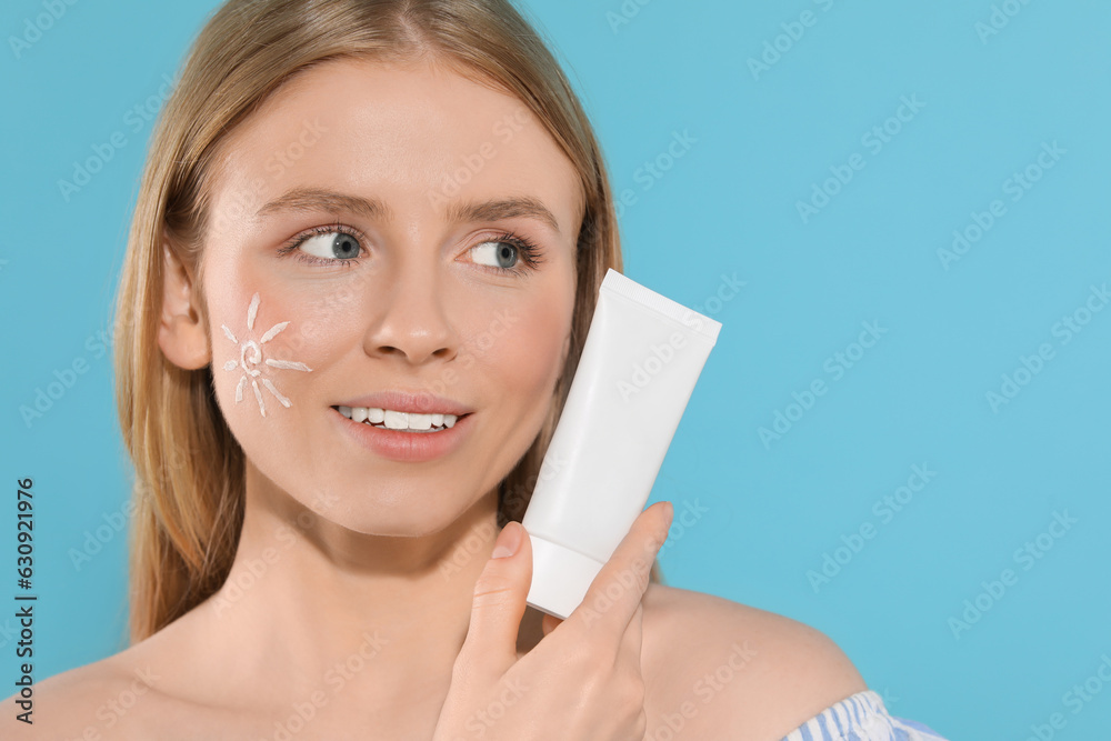 Beautiful young woman with sun protection cream on light blue background, space for text Beautiful young woman with sun protection cream on light blue background, space for text