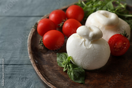 Delicious burrata cheese with tomatoes on grey wooden table  closeup. Space for text