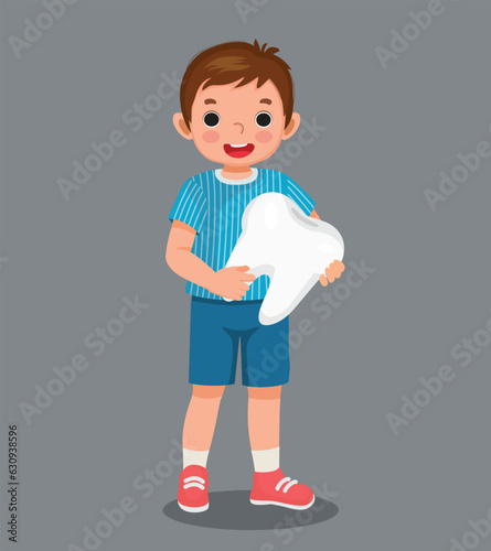 Cute little boy holding big tooth