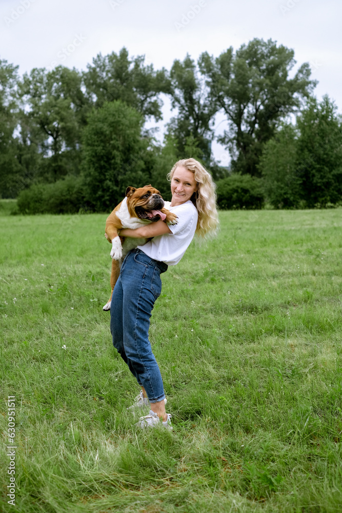 Fototapeta premium young woman playing with English Bulldog at park