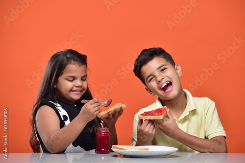 Portraits of kids eating bread and jam in breakfast