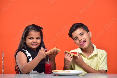 Portraits of kids eating bread and jam in breakfast