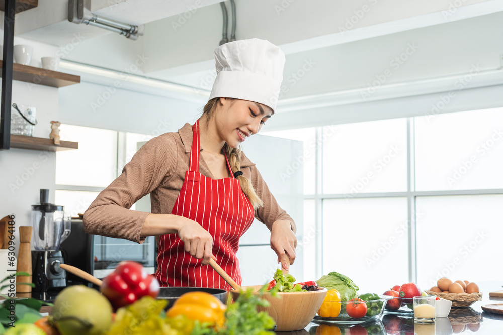 Young beautiful asian female chef cooking breakfast salad in the kitchen. Happy asian woman preparing healthy food with ingredient. Chef in uniform in the kitchen. Young beautiful asian female chef cooking breakfast salad in the kitchen. Happy asian woman preparing healthy food with ingredient. Chef in uniform in the kitchen.