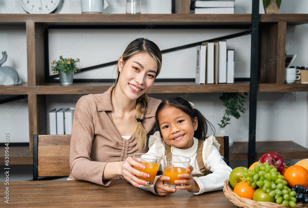 Mother and daughter drinking orange juice at home.