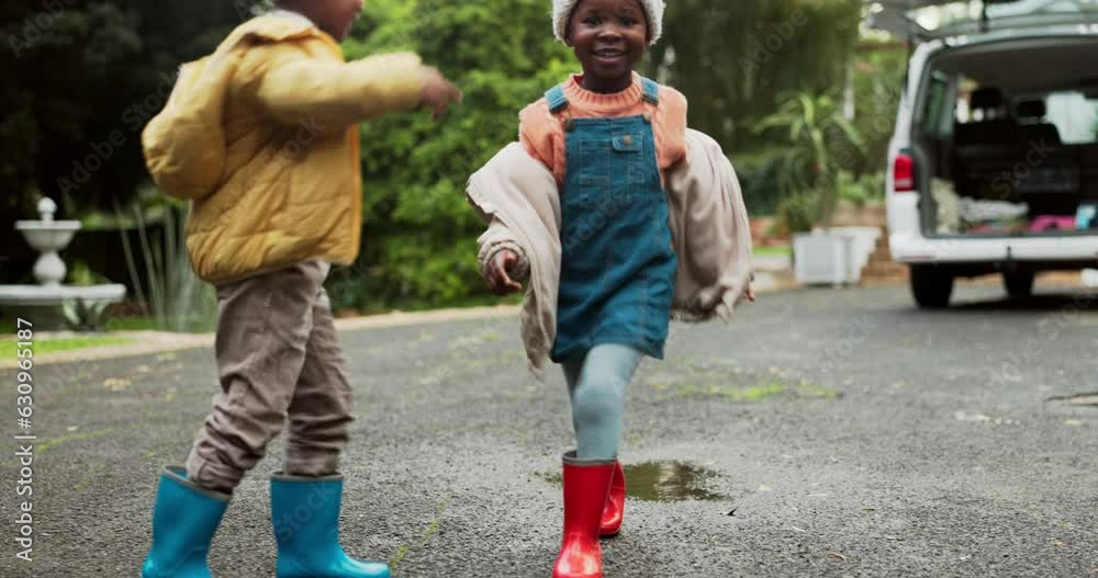 Children, driveway and jumping in water puddle on winter holiday travel, happiness and fun together. Siblings, rain boots and playing on asphalt with splash, kids with energy and vacation in Africa.
