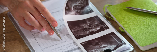 Female doctor analyzes results of patient's medical examination at her desk in clinic. photo