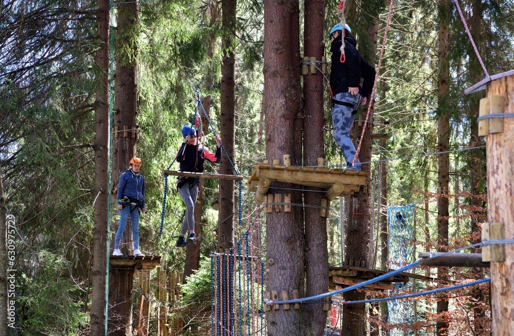 Man and a woman climb the wooden stairs at a height in amusement rope park