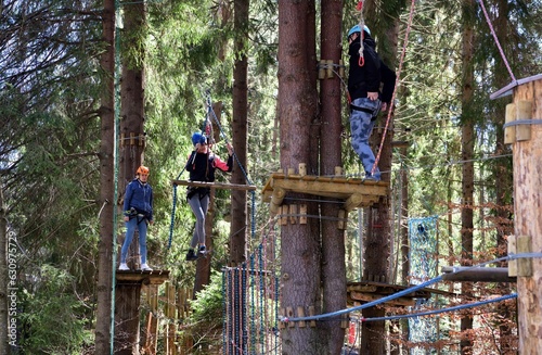 Obraz na płótnie Man and a woman climb the wooden stairs at a height in amusement rope park w salonie