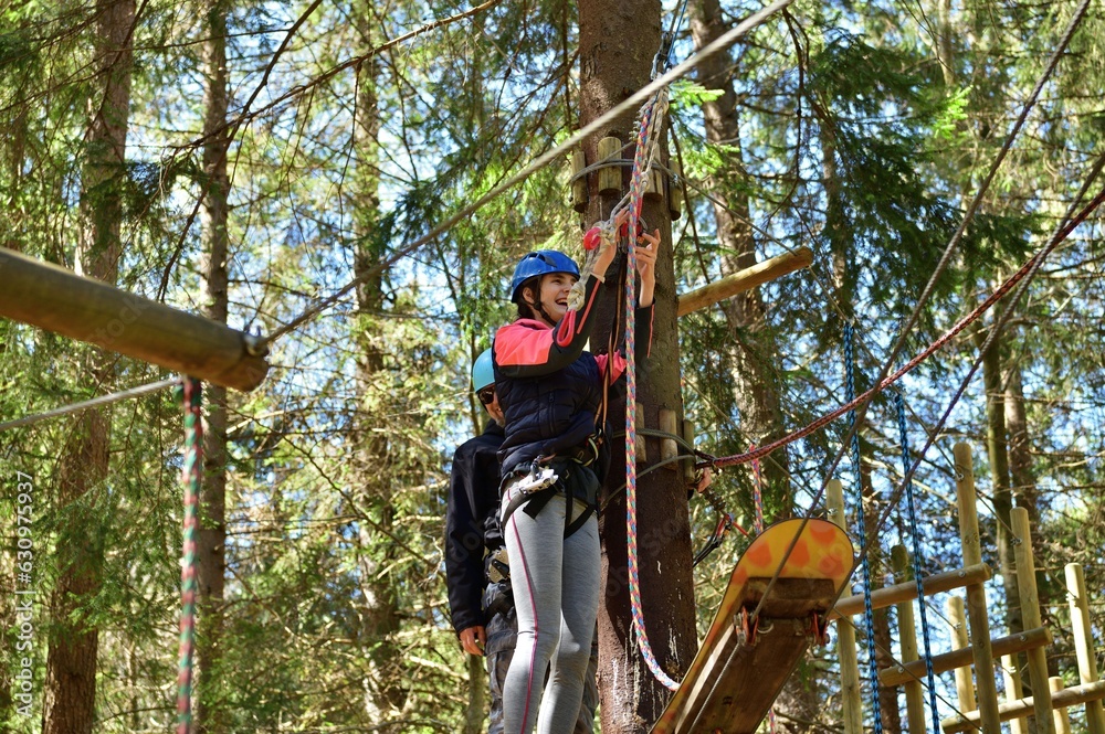 Man and a woman climb the wooden stairs at a height in amusement rope park