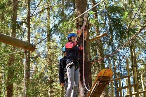 Obraz na płótnie Man and a woman climb the wooden stairs at a height in amusement rope park w salonie