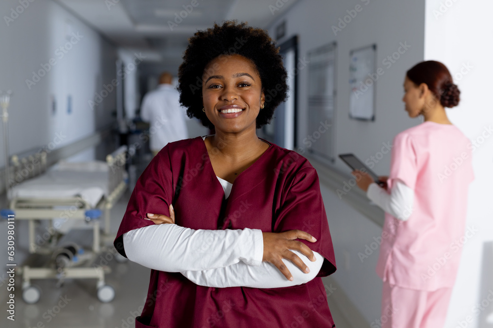 Portrait of happy african american female doctor wearing scrubs in corridor at hospital Portrait of happy african american female doctor wearing scrubs in corridor at hospital