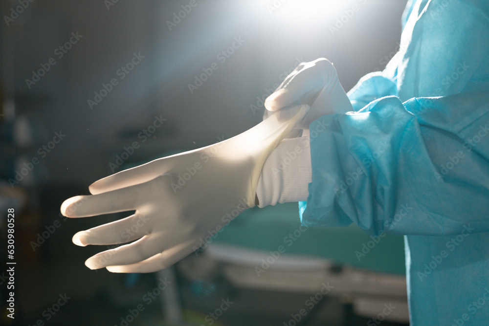 Midsection of biracial female surgeon wearing surgical gown and gloves