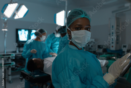 Portrait of african american female surgeon wearing surgical gown in operating theatre at hospital