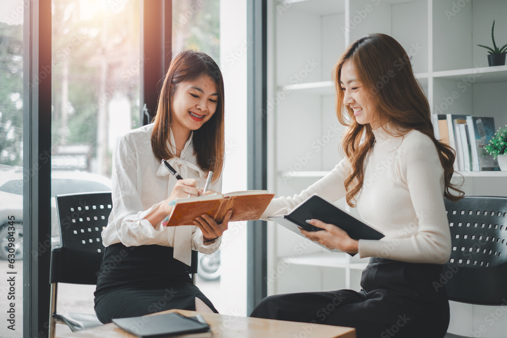 Two diverse happy businesswomen discussing business project working together in office, serious female advisor and client talking at meeting Two diverse happy businesswomen discussing business project working together in office, serious female advisor and client talking at meeting