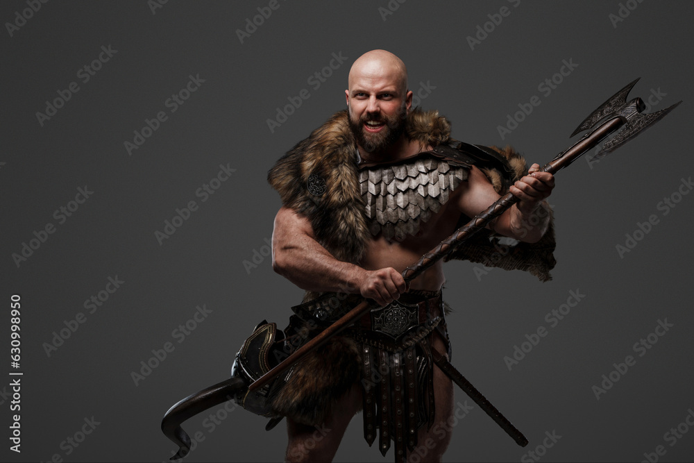 An angry and yelling bearded Viking warrior wearing fur and lightweight armor against a gray backdrop