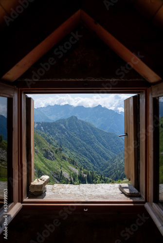 Canvas Print The view the green mountains from the window in a small hut, Bivacco, in the Italian Alps