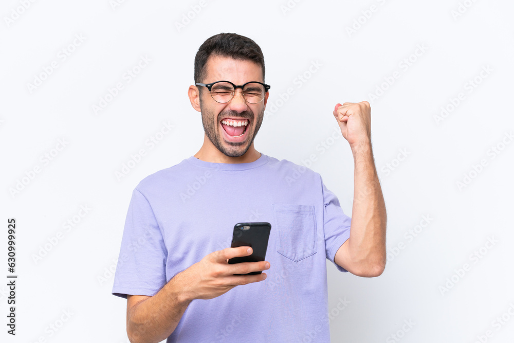 Young caucasian man isolated on white background with phone in victory position
