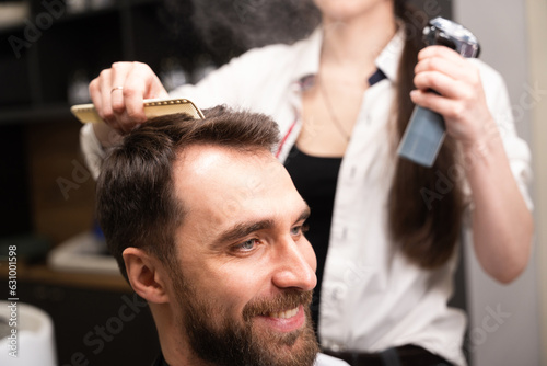 Craftswoman in a barbershop is styling a clients hair