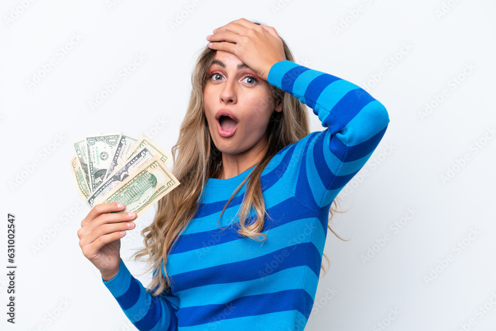 Young Uruguayan woman taking a lot of money isolated on white background doing surprise gesture while looking to the side Young Uruguayan woman taking a lot of money isolated on white background doing surprise gesture while looking to the side