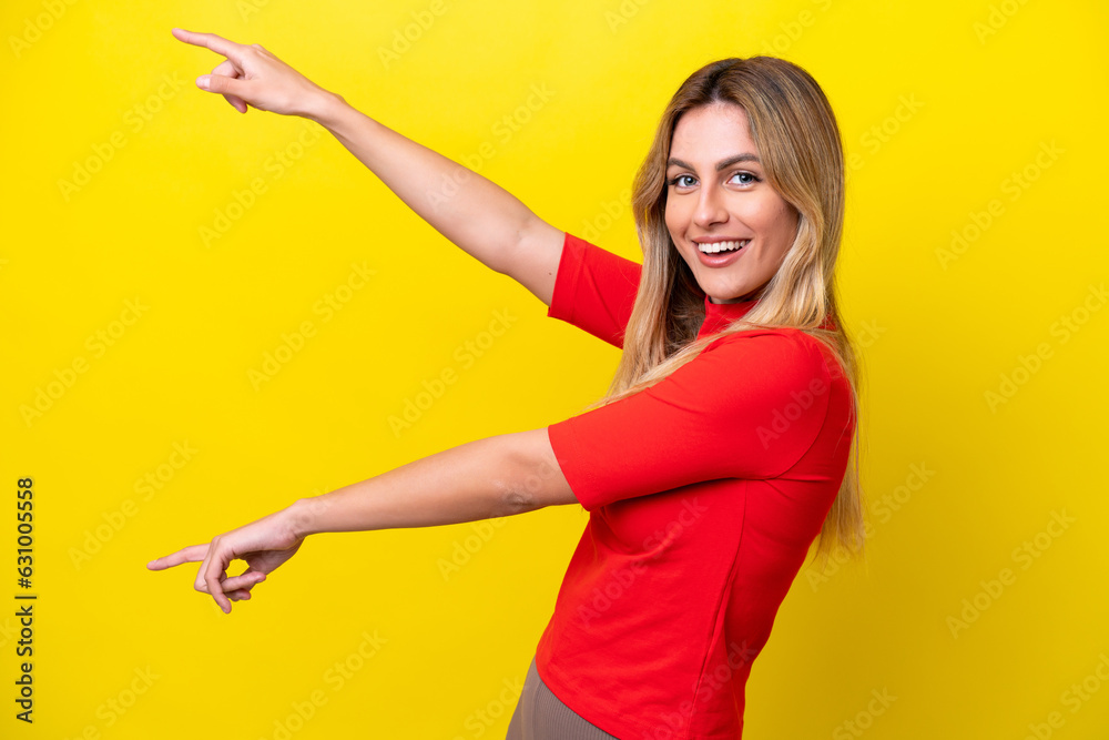 Young Uruguayan woman isolated on yellow background pointing finger to the side and presenting a product Young Uruguayan woman isolated on yellow background pointing finger to the side and presenting a product