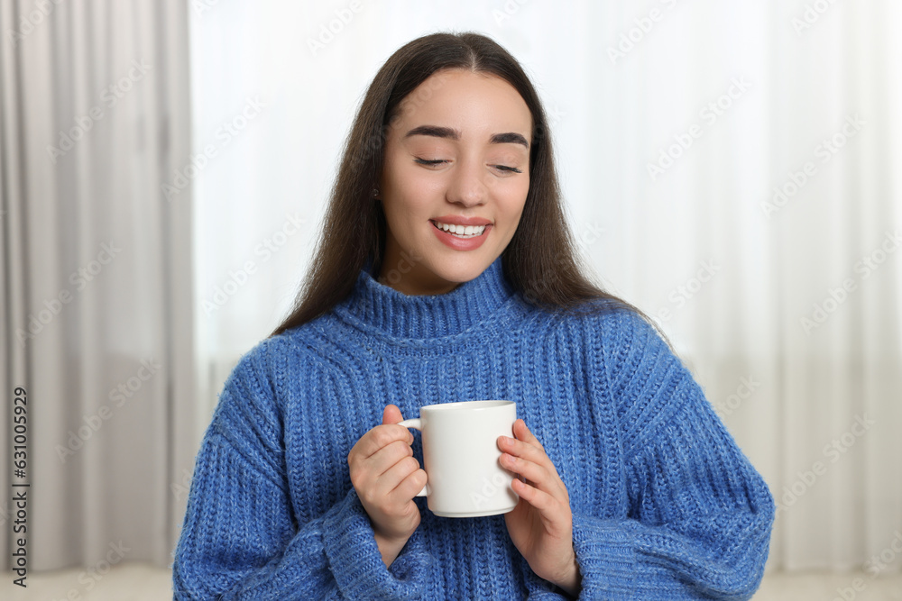 Happy young woman holding white ceramic mug at home Happy young woman holding white ceramic mug at home