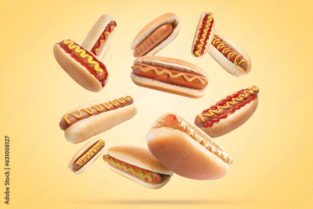 Many tasty hot dogs falling on beige background Many tasty hot dogs falling on beige background