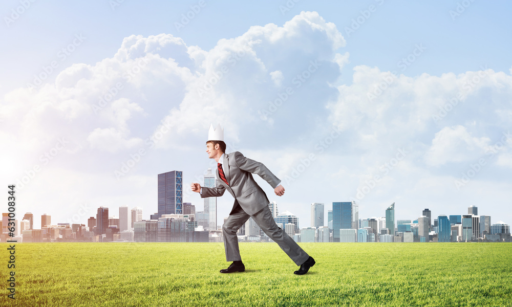 King businessman in elegant suit running on green grass and modern cityscape at background King businessman in elegant suit running on green grass and modern cityscape at background