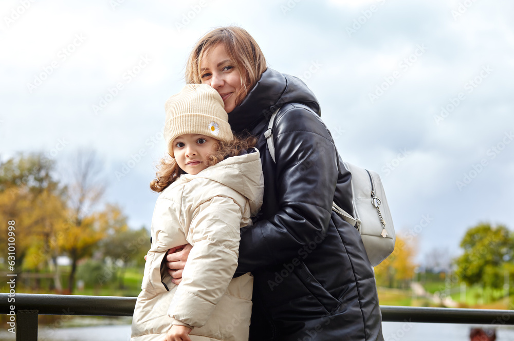 Hello october. Mother and daughter are walking in the autumn city park. Parent and little child having fun outdoors Hello october. Mother and daughter are walking in the autumn city park. Parent and little child having fun outdoors