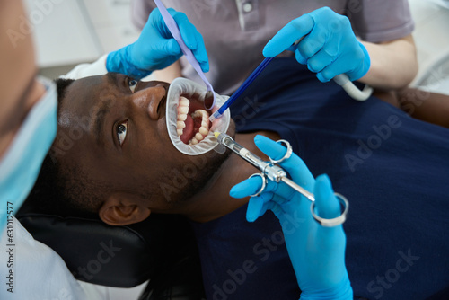 Woman dentist doing anaesthetic injection to man with mouth retractor